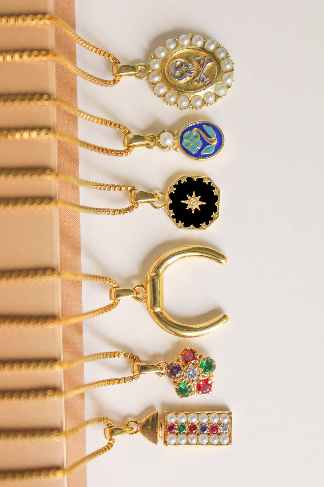 Hero image — all Ether pendant necklaces in 18k gold vermeil laying on book, flat lay, Ether Jewelry