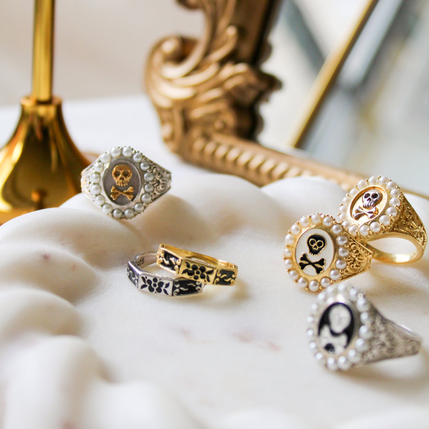 Mourning Memento Heirloom 18k gold vermeil ring stacked with other Victorian mourning pieces on marble plate by candle and mirror, Ether Jewelry