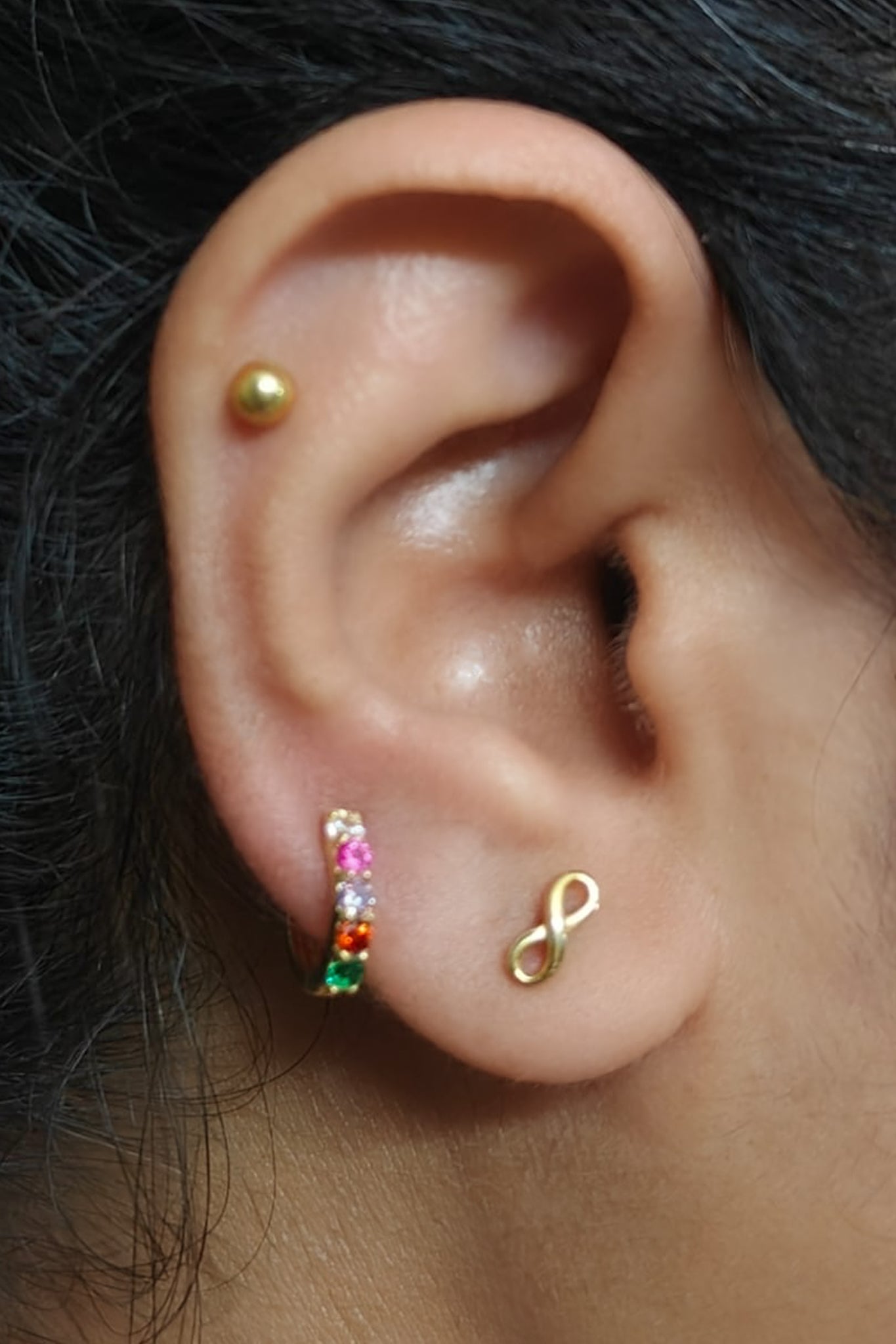 18k gold vermeil Regard Huggies stacked with other earrings on model ear, acrostic REGARD CZ huggie hoops, Ether Jewelry