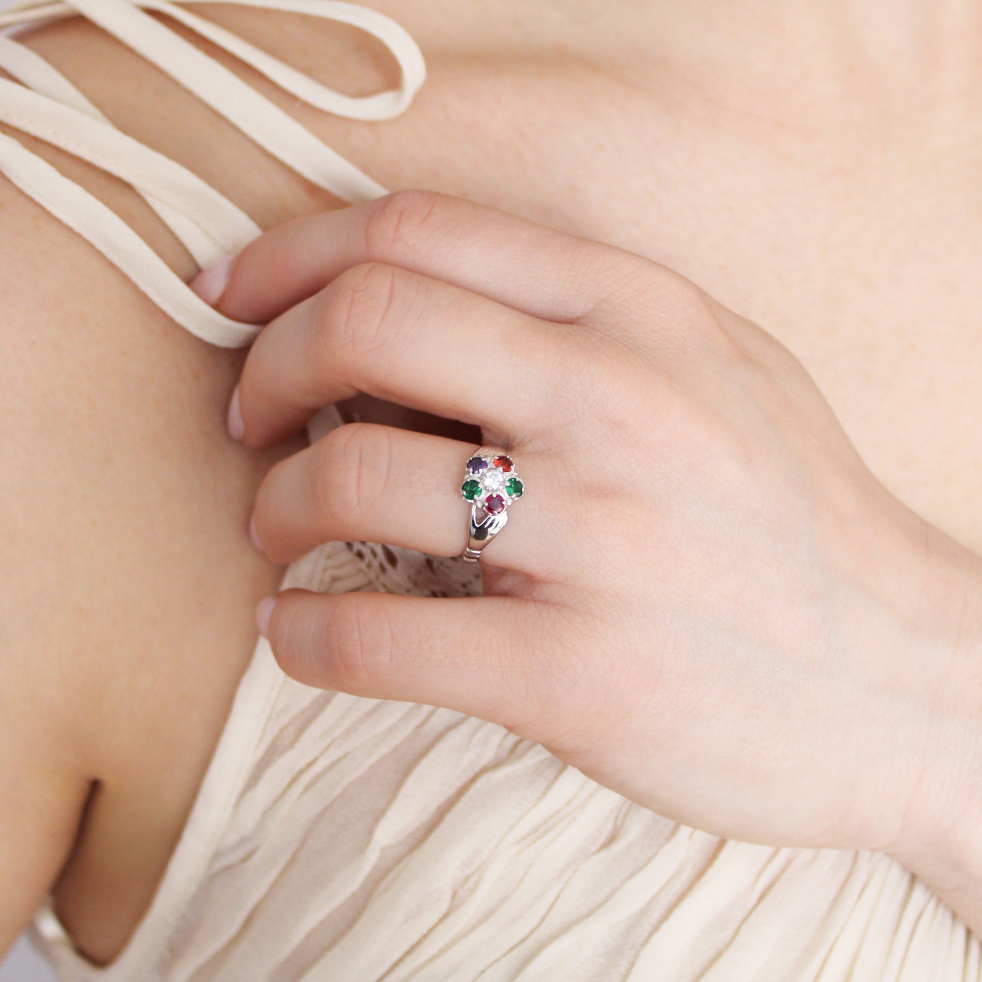 Regard Bloom Ring in sterling silver worn on model hand on chest in beige dress, floral REGARD acrostic cluster ring, Ether Jewelry