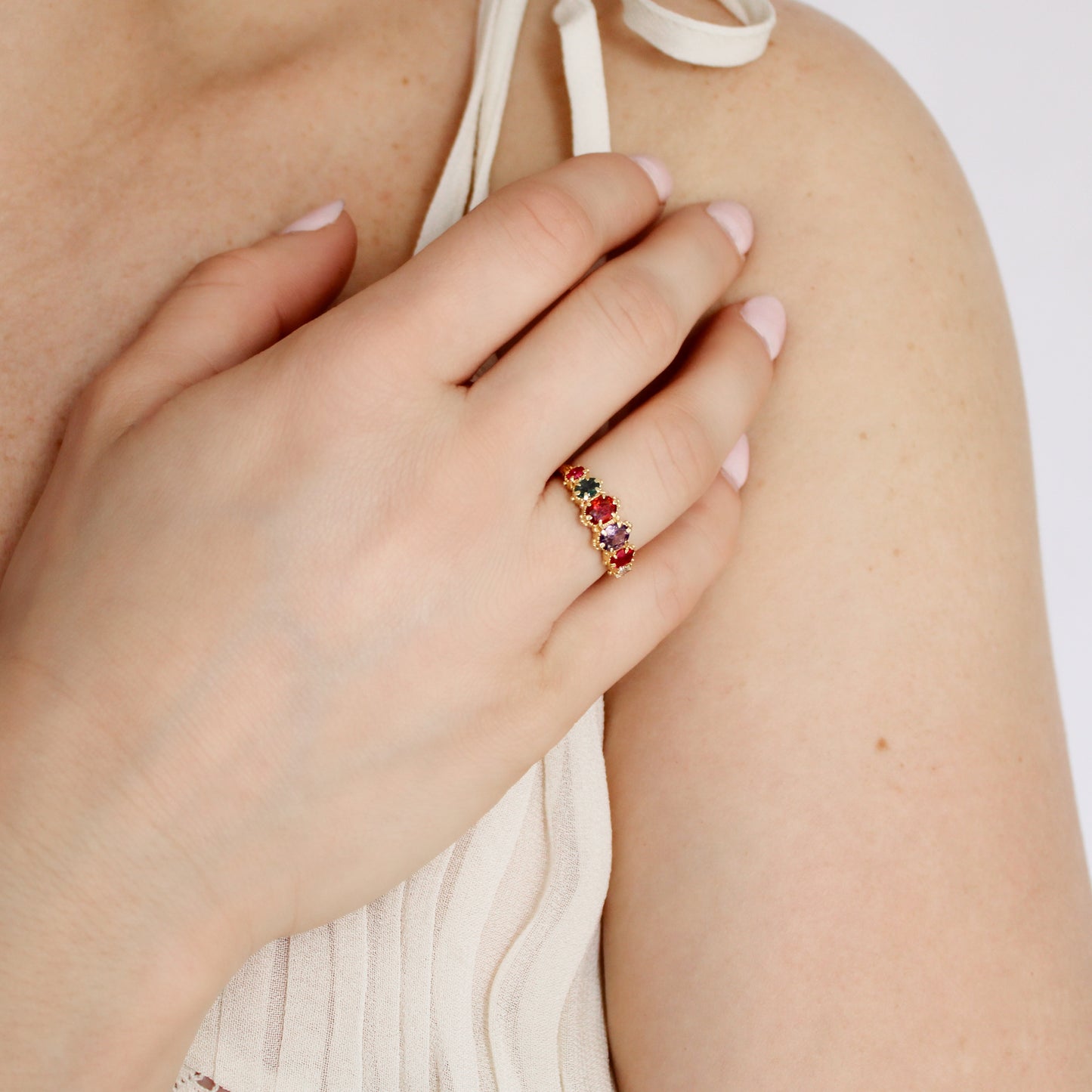 Crowned Jewel Ring in 18k gold vermeil worn on model hand on chest in beige dress, oval REGARD acrostic CZ ring, Ether Jewelry