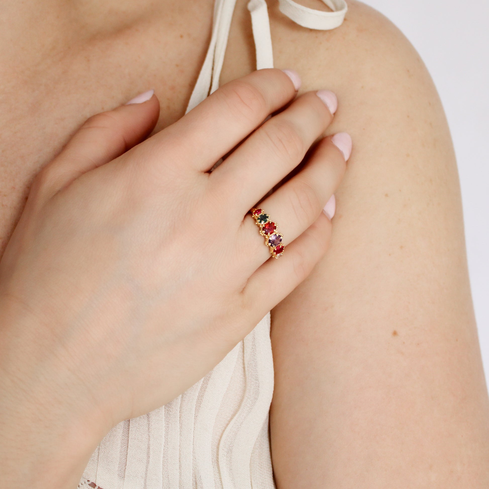 Crowned Jewel Ring in 18k gold vermeil worn on model hand on chest in beige dress, oval REGARD acrostic CZ ring, Ether Jewelry
