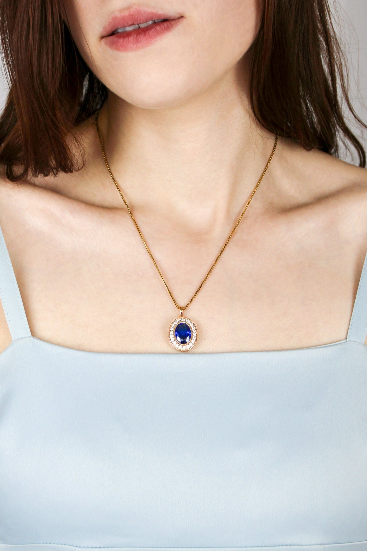 Close-up of gold Heartline Necklace catching light, blue center stone radiating quiet power and beauty, Ether Jewelry