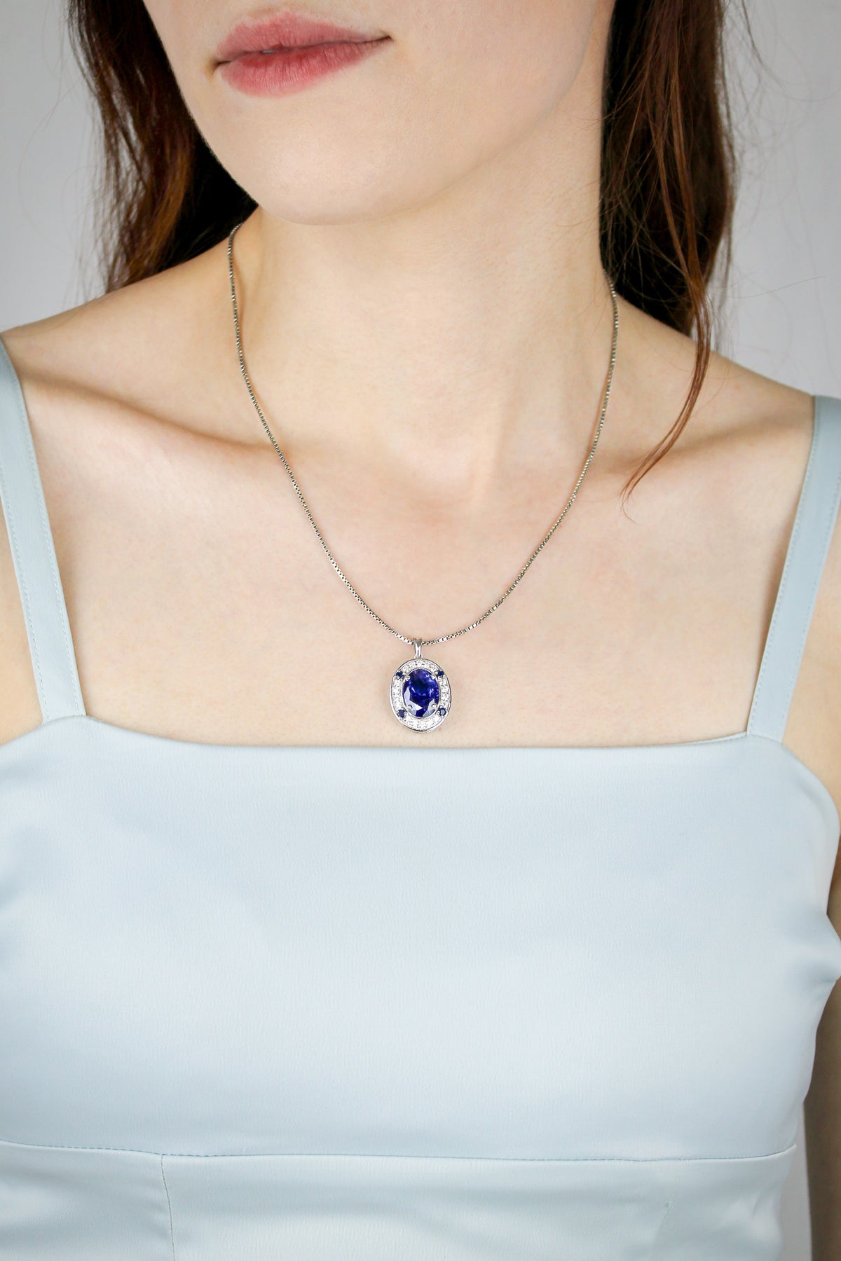 Close-up of silver Heartline Necklace resting on model’s collarbone, radiant blue gemstone catching light, Ether Jewelry