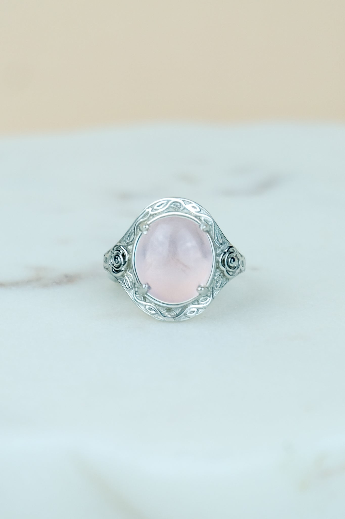 sterling Silver romantic heir signet ring with a pink quartz gemstone and flower engravings on a marble surface