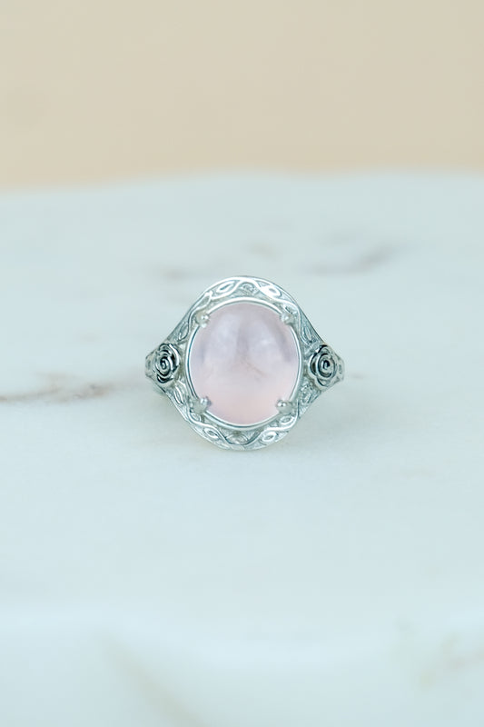 sterling Silver romantic heir signet ring with a pink quartz gemstone and flower engravings on a marble surface