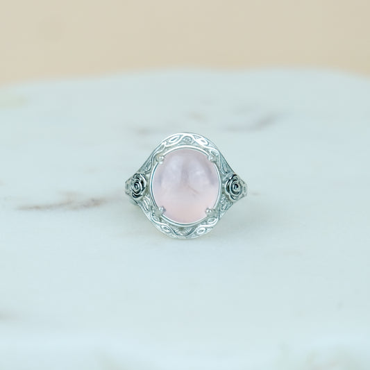 sterling Silver romantic heir signet ring with a pink quartz gemstone and flower engravings on a marble surface