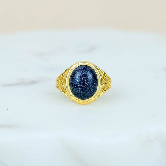 Gold night keeper signet ring with a blue sandstone on a marble background