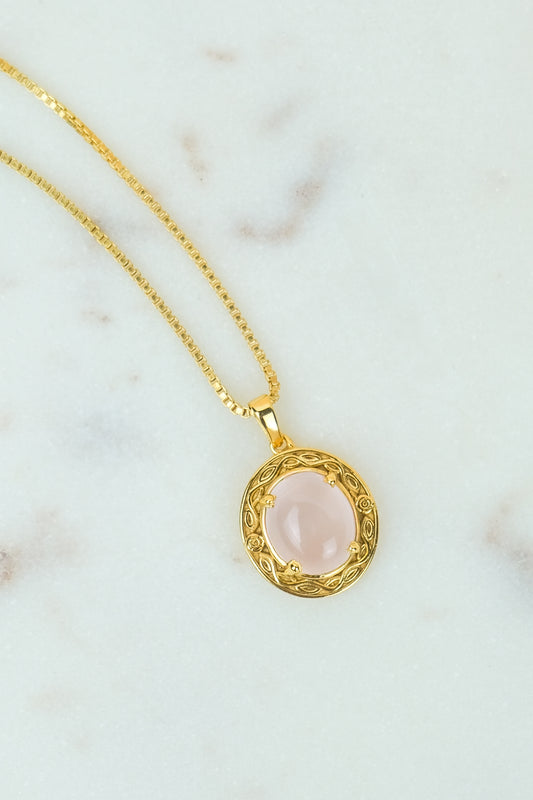 Gold Romantic Heir necklace with a pink quartz stone pendant on a marble surface