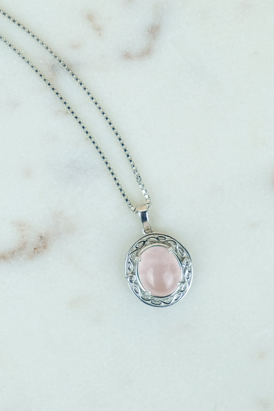 Romantic Heir Necklace with a pink quartz stone pendant on a marble background
