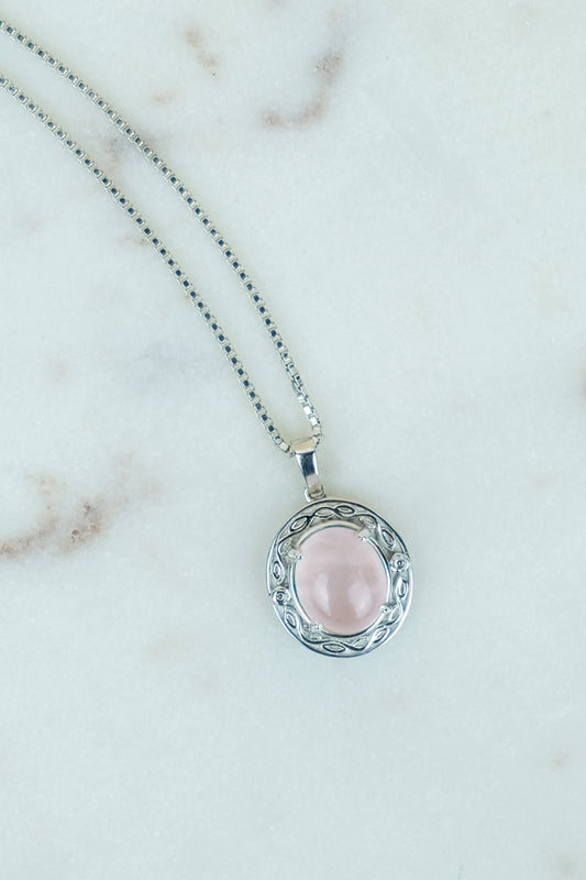 Romantic Heir Necklace with a pink quirtz stone pendant on a marble background