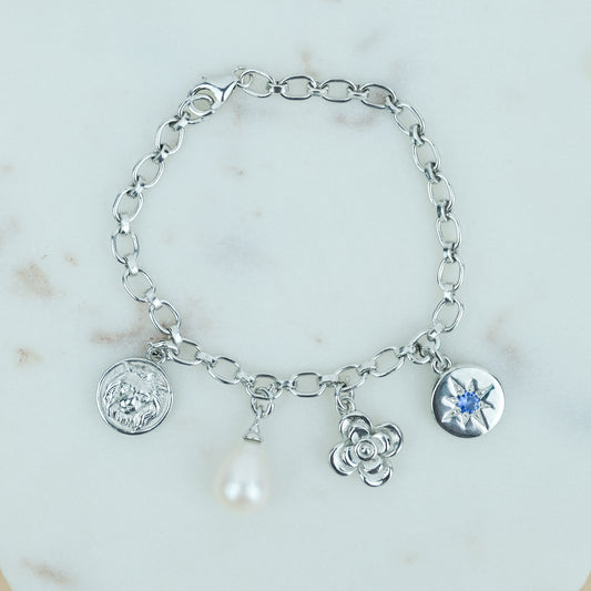 the archivist bracelet Silver bracelet rhodium plated with various charms on a marble background