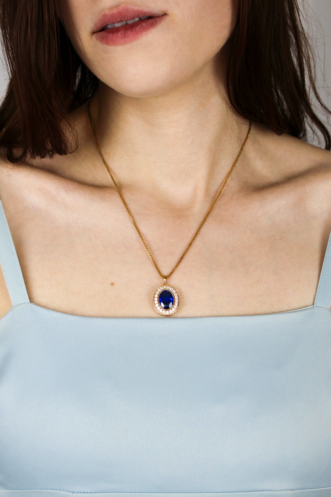 Close-up of gold Heartline Necklace catching light, blue center stone radiating quiet power and beauty.