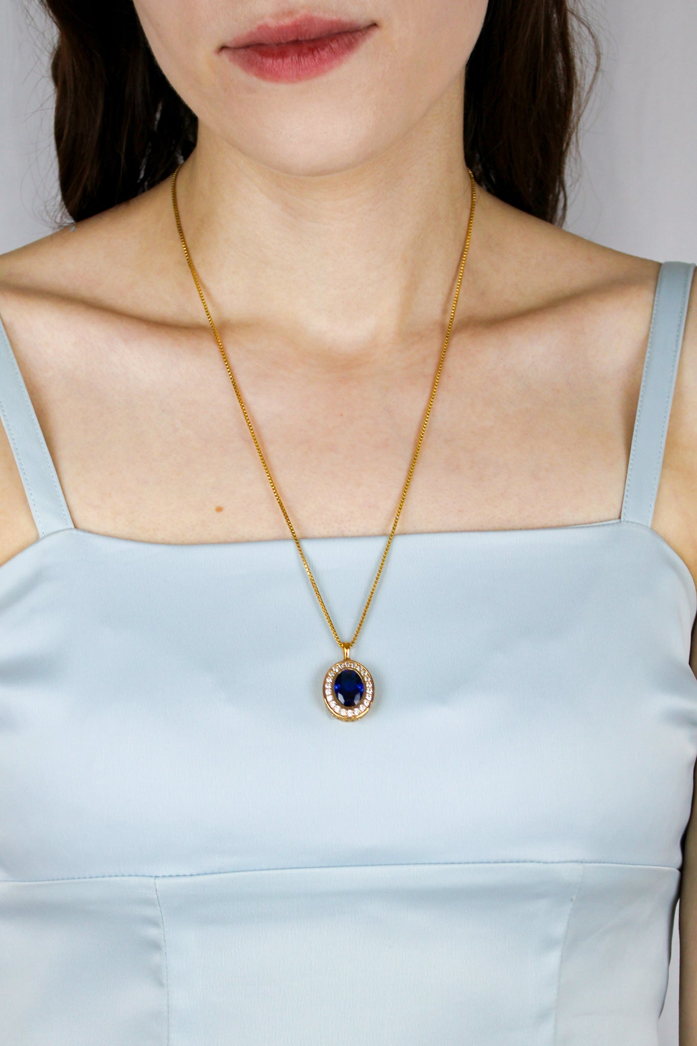 Model wearing Heartline Necklace in gold, sapphire gemstone resting elegantly at collarbone — inspired by Princess Diana’s grace.