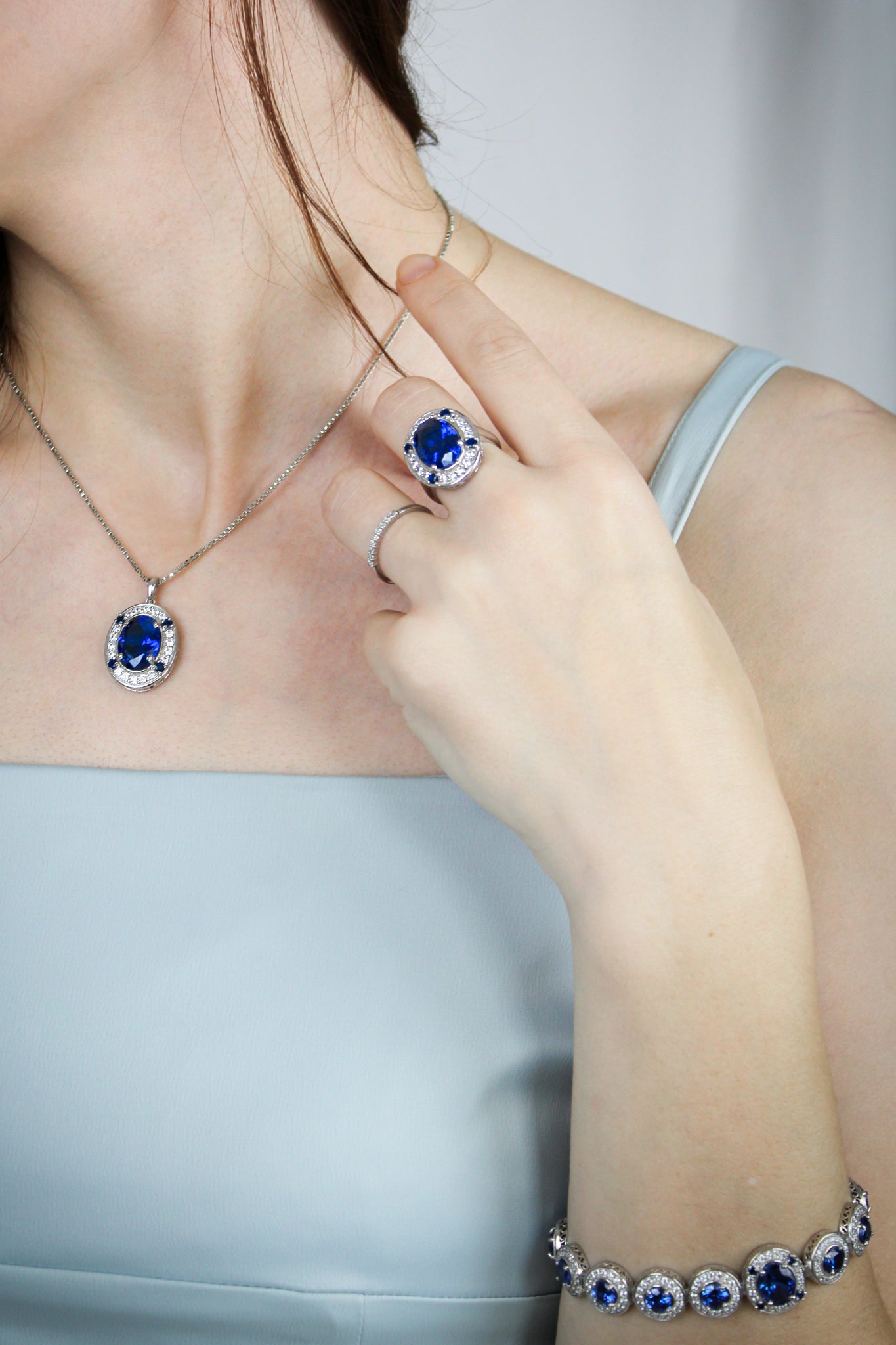Diana Legacy Jewelry set with necklace, ring, and bracelet featuring blue gemstones on a neutral background.
