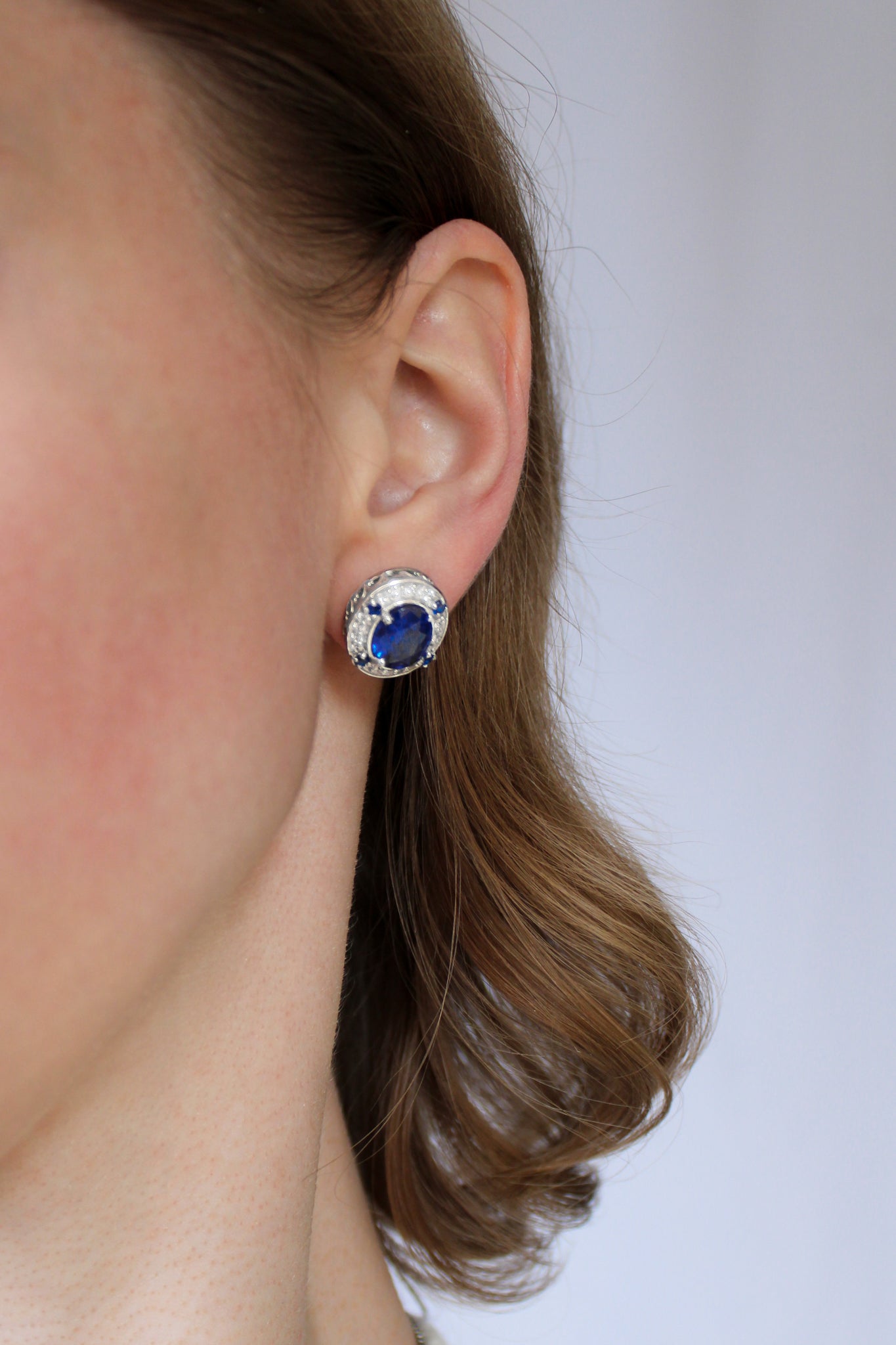 Model portrait highlighting silver Sovereign Stud Earrings, radiant blue gemstones symbolizing grace and remembrance.