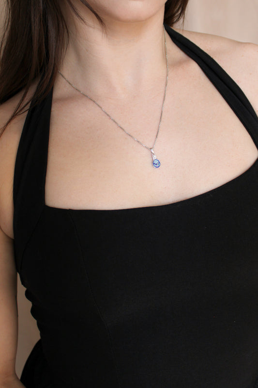 Mourning Bloom Necklace in sterling silver worn on model, blue enamel forget-me-not pendant front view, Ether Jewelry