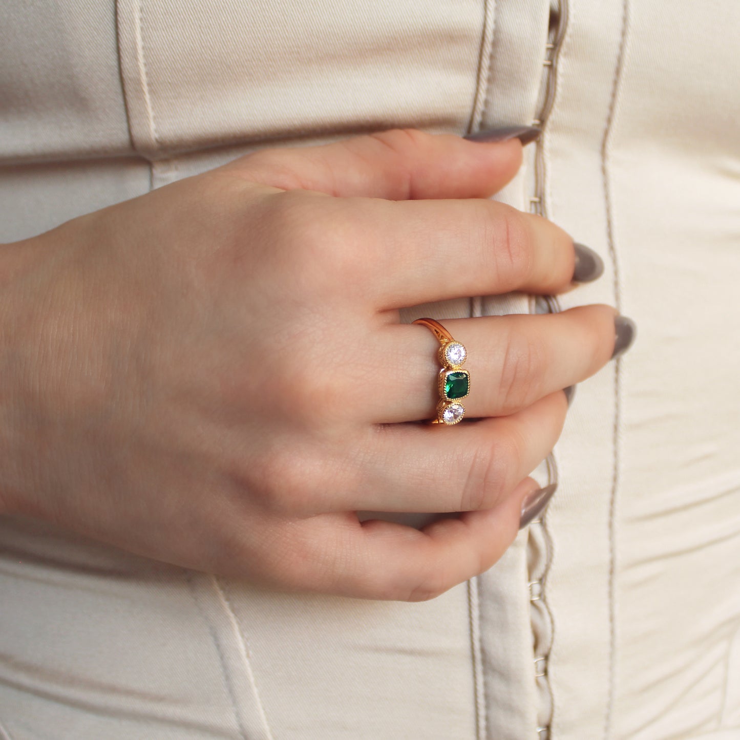 Edwardian Three Stone 18k gold vermeil ring on model hands held at stomach in beige dress, green CZ center stone, Ether Jewelry