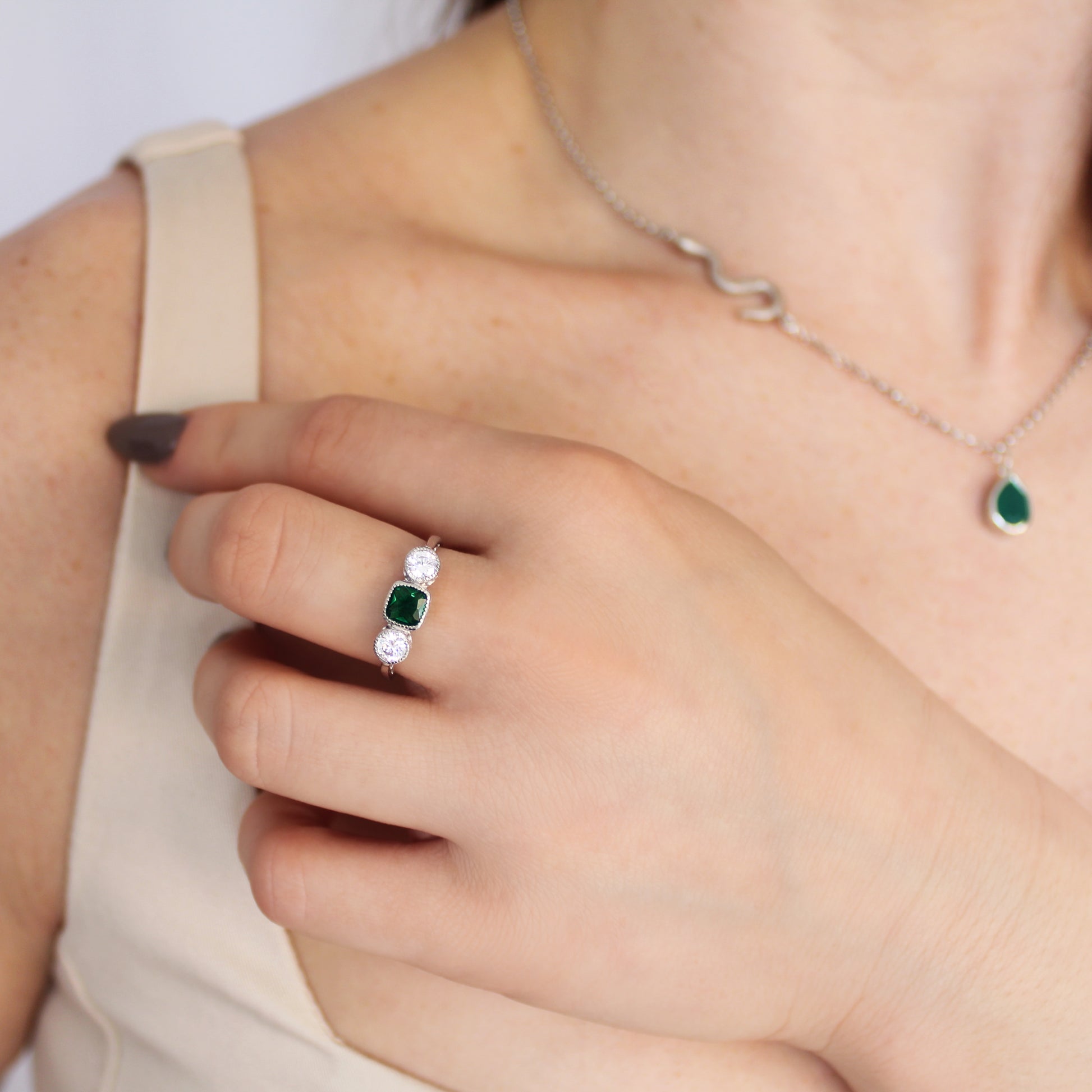 Edwardian Three Stone ring in sterling silver worn on model in beige dress, hand near chest, green CZ three stone ring, Ether Jewelry