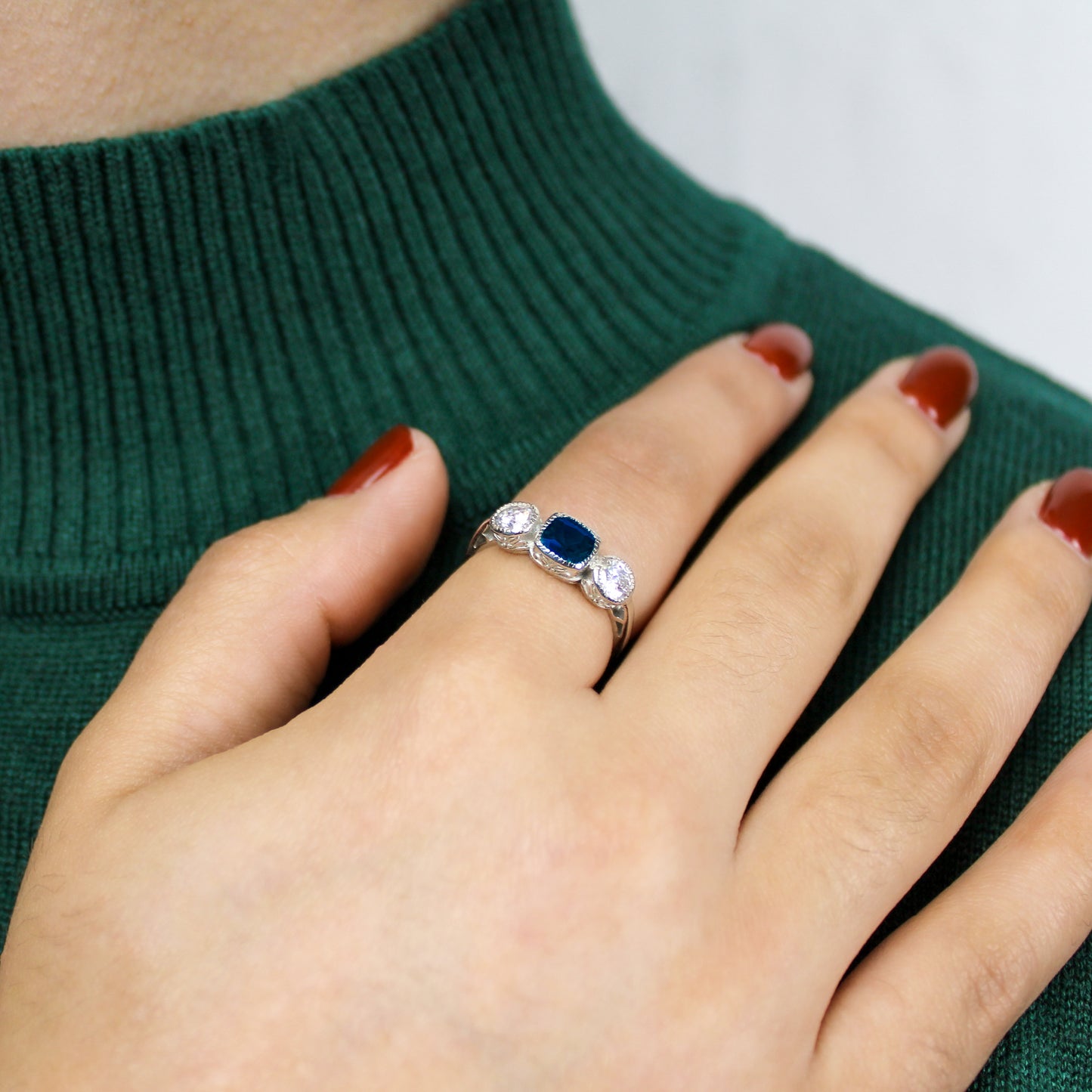 Edwardian Empress ring in sterling silver worn on model hand across shoulder, blue CZ three stone milgrain ring, Ether Jewelry