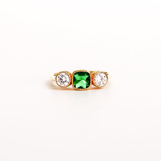 Three Stone Edwardian Ring on white background, square center emerald gemstone, two white side gemstones, ether jewelry