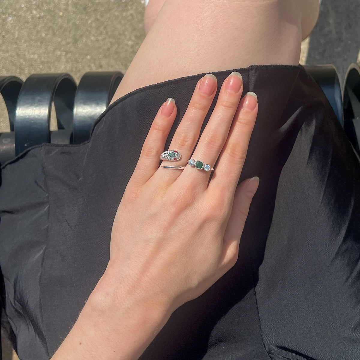 Sterling silver serpent ring styled on model hand in black dress with Edwardian three stone ring, top angle view, Ether Jewelry