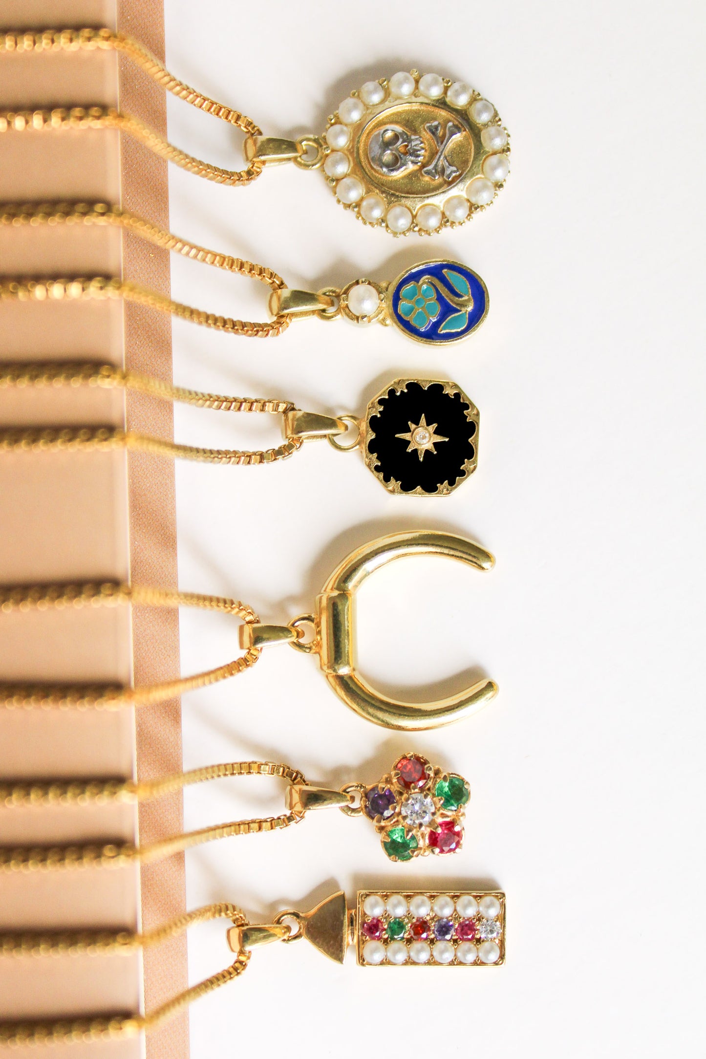 All Ether pendant necklaces in 18k gold vermeil laying on book, flat lay, Ether Jewelry