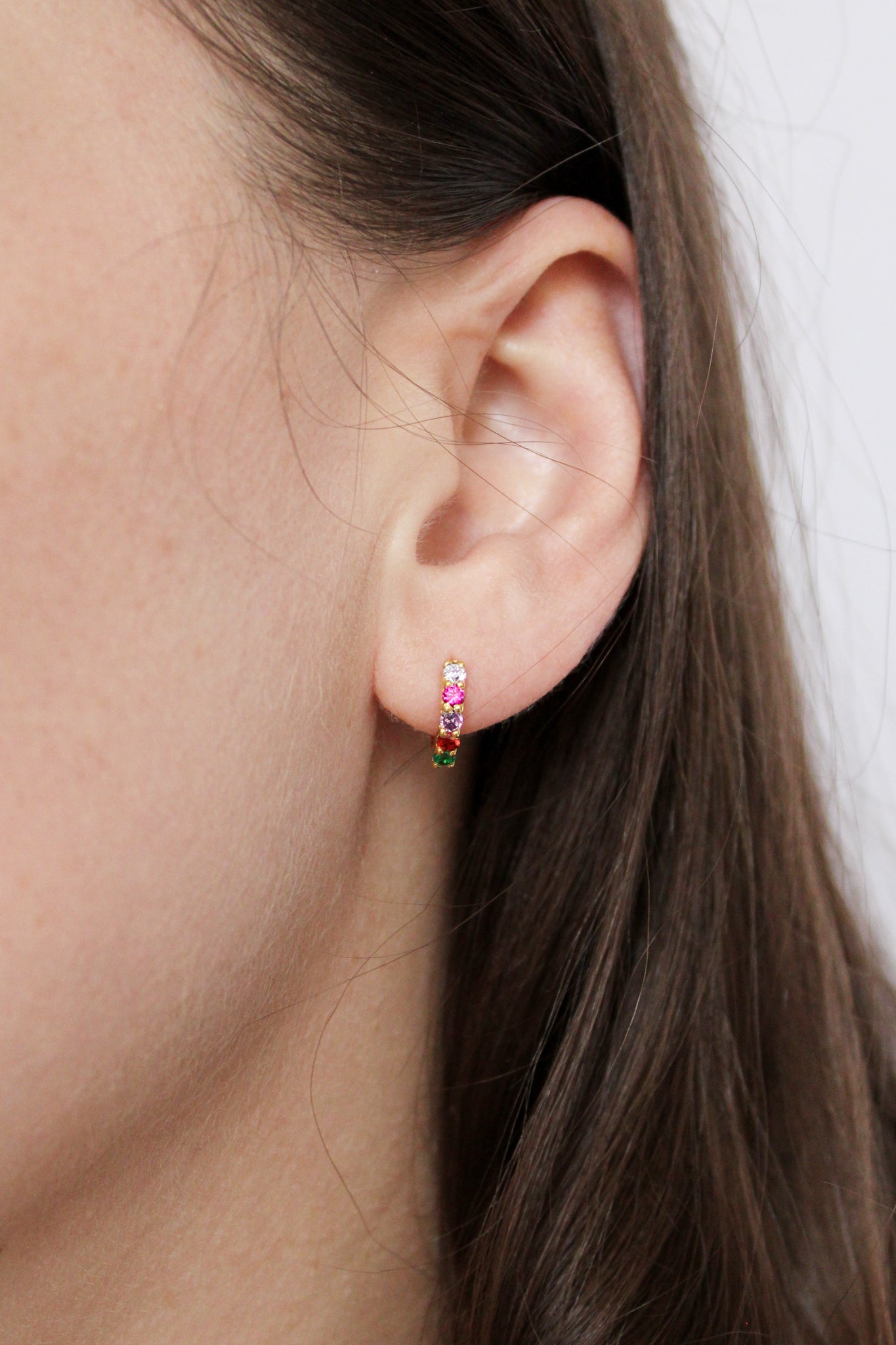 18k gold vermeil Regard Huggies close-up on model ear, colorful acrostic REGARD CZ stones on huggie hoop, Ether Jewelry