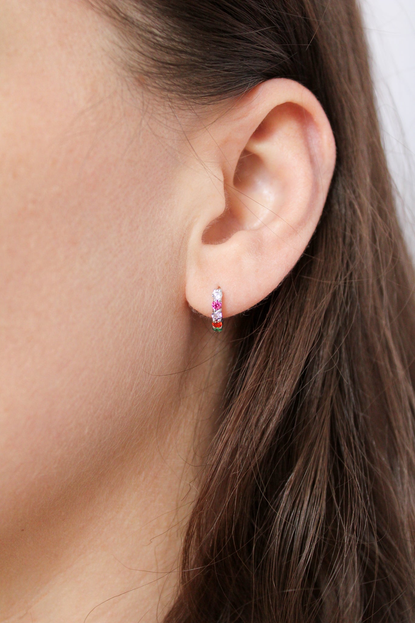 Regard Huggies sterling silver on model ear from another angle, acrostic CZ huggie hoop earrings, Ether Jewelry