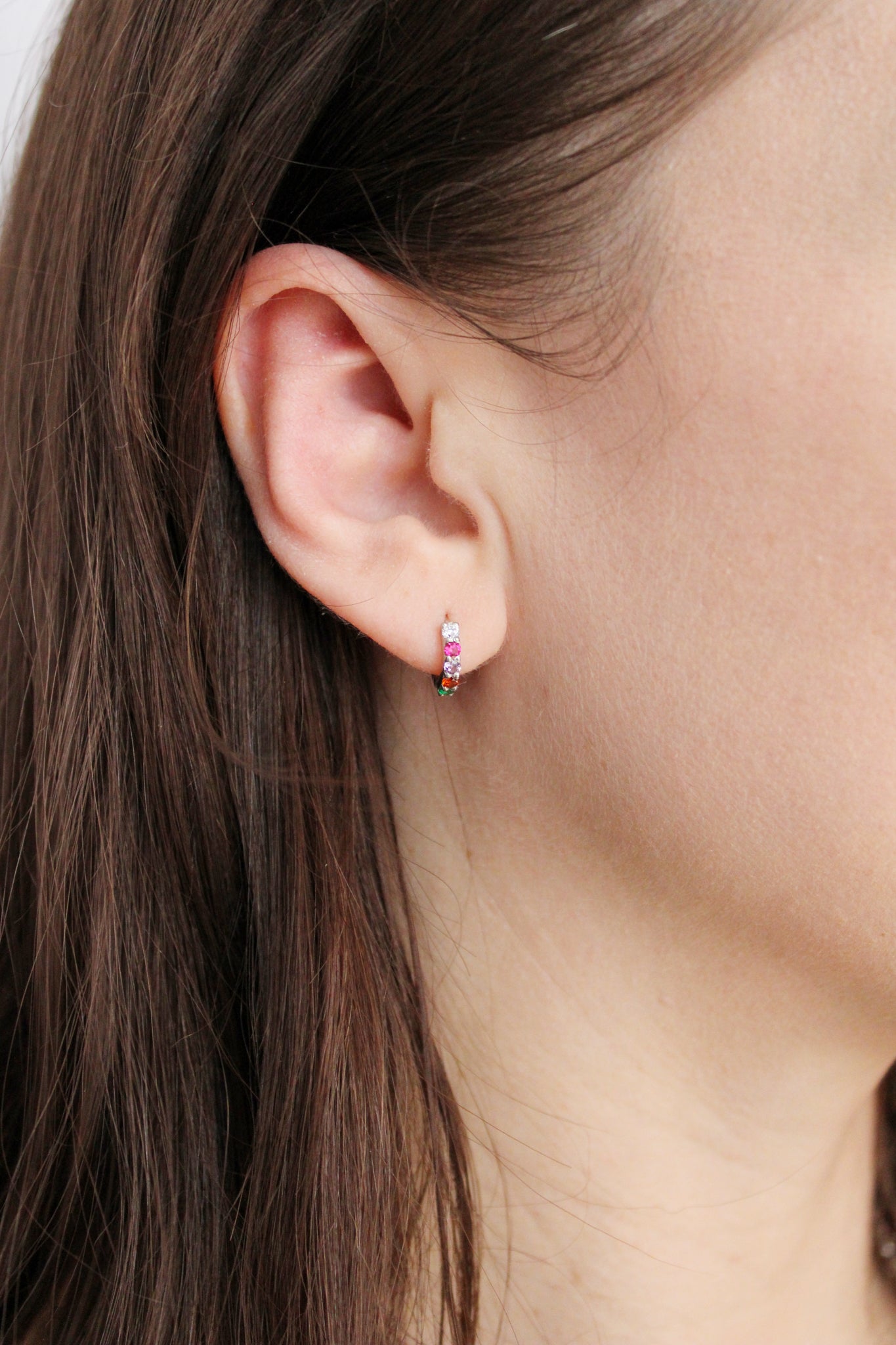 Regard Huggies in sterling silver on model ear, acrostic REGARD CZ huggie hoop earrings, Ether Jewelry