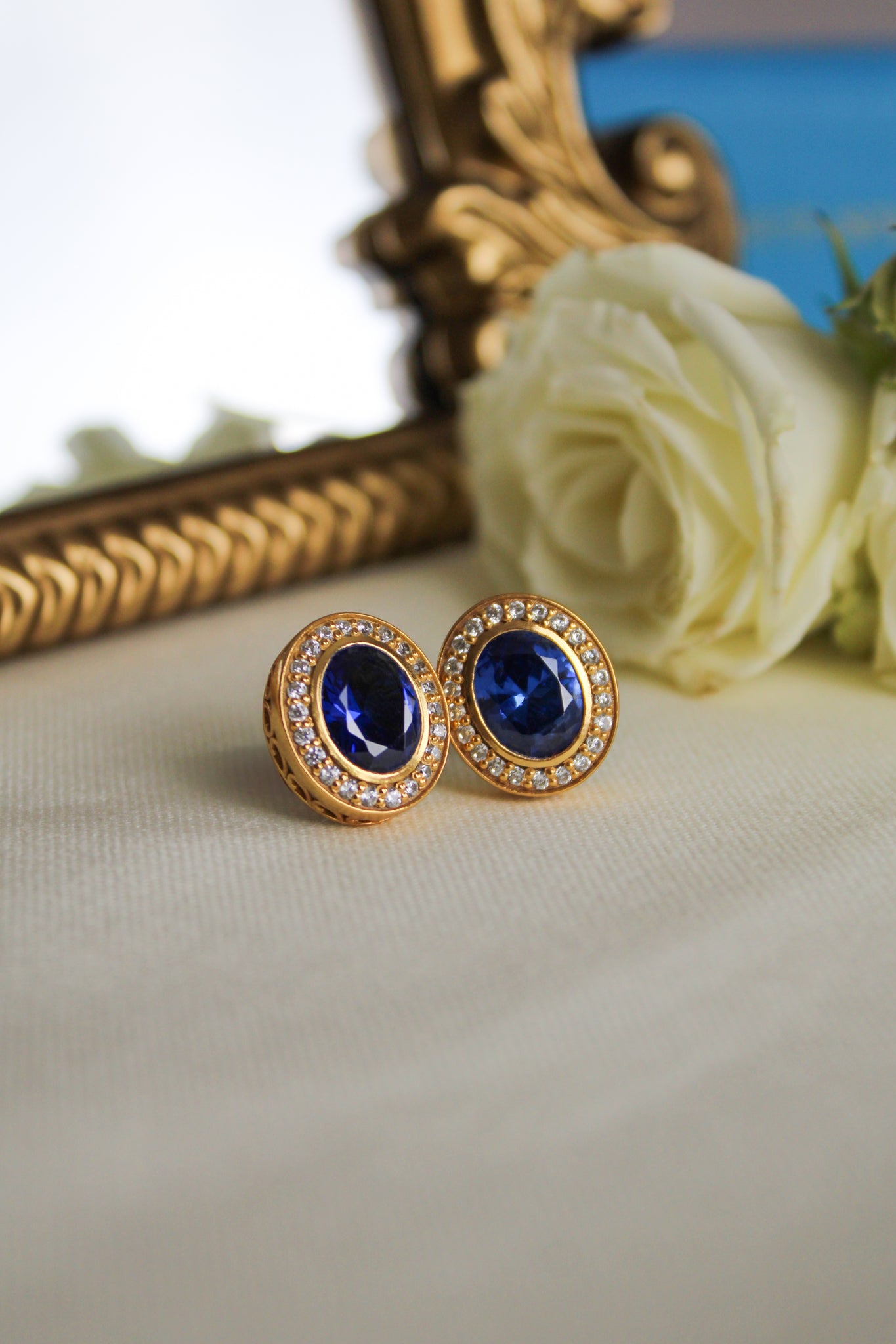 Close-up of 18k gold vermeil Sovereign Earrings featuring luminous sapphire and brilliant accents.