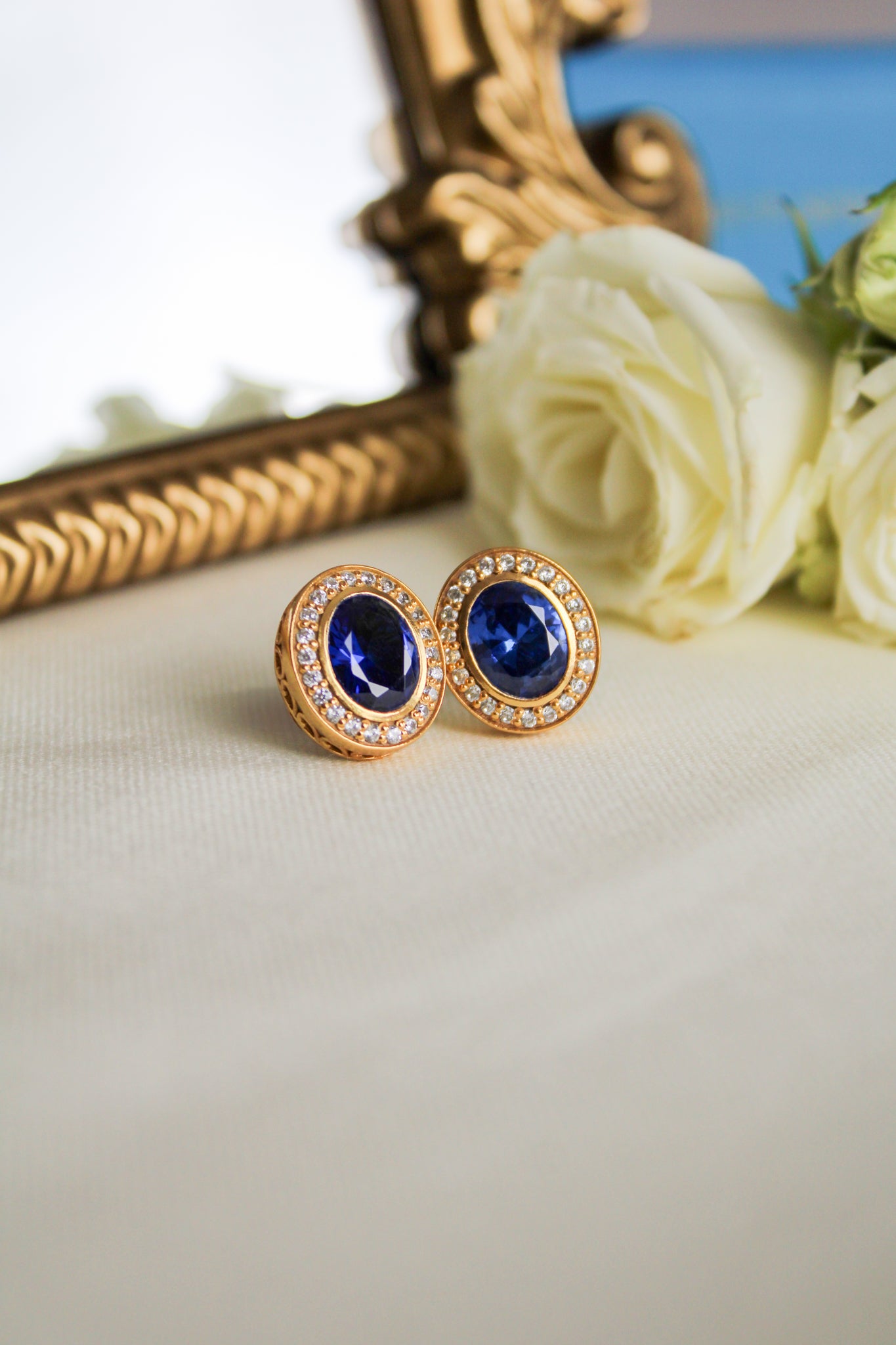 Close-up of 18k gold vermeil Sovereign Earrings featuring luminous sapphire and brilliant accents, Ether Jewelry