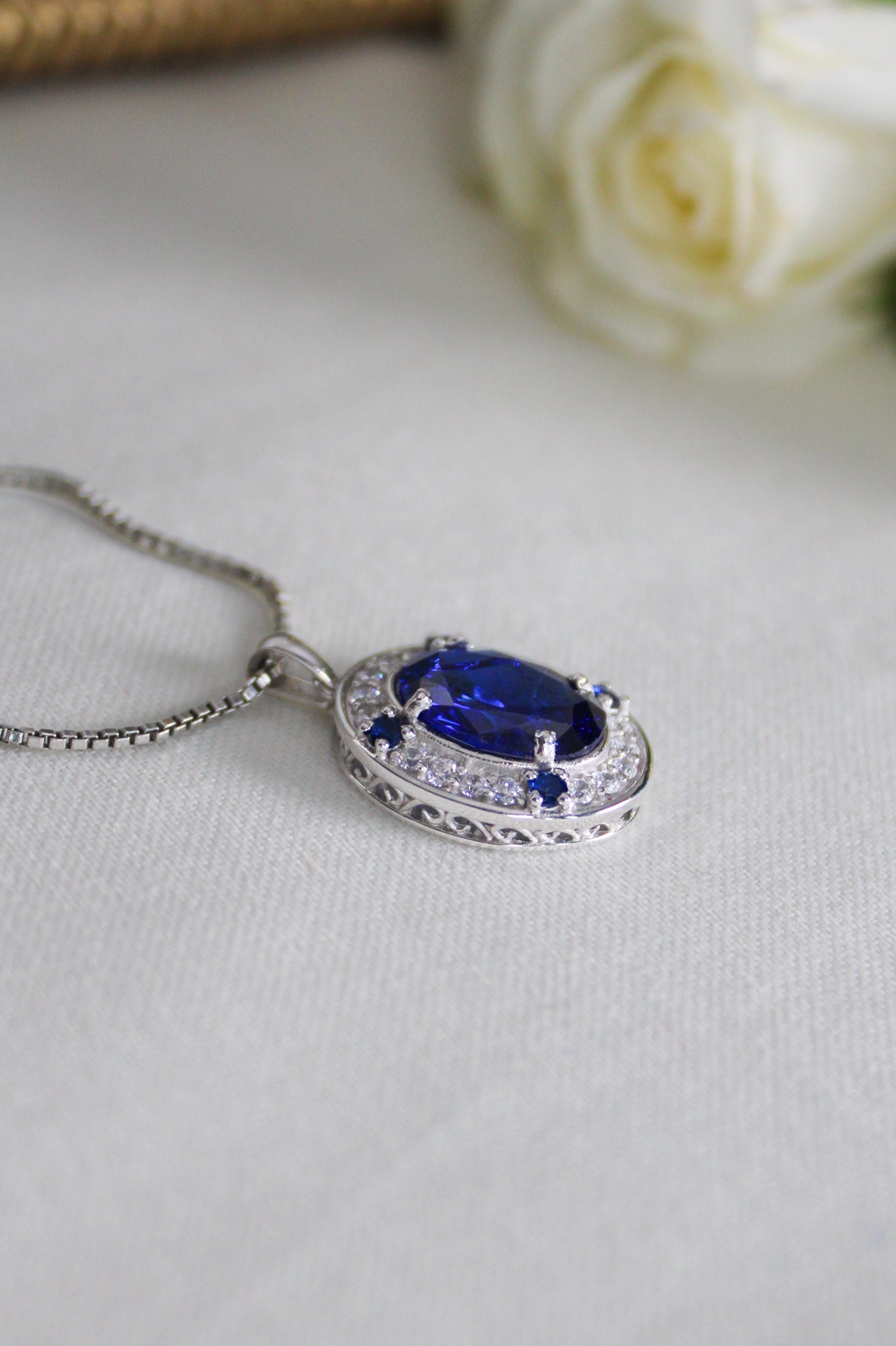 Detailed macro of silver Heartline Necklace showing radiant blue gemstone and engraved gallery setting.