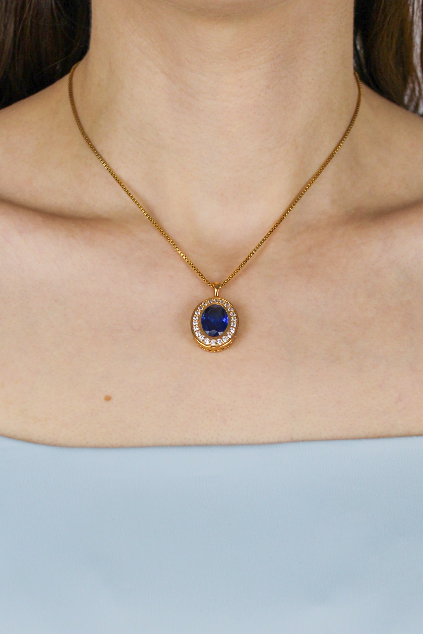Close-up of model’s neckline showcasing gold Heartline Necklace, sapphire gemstone symbolizing eternal love.