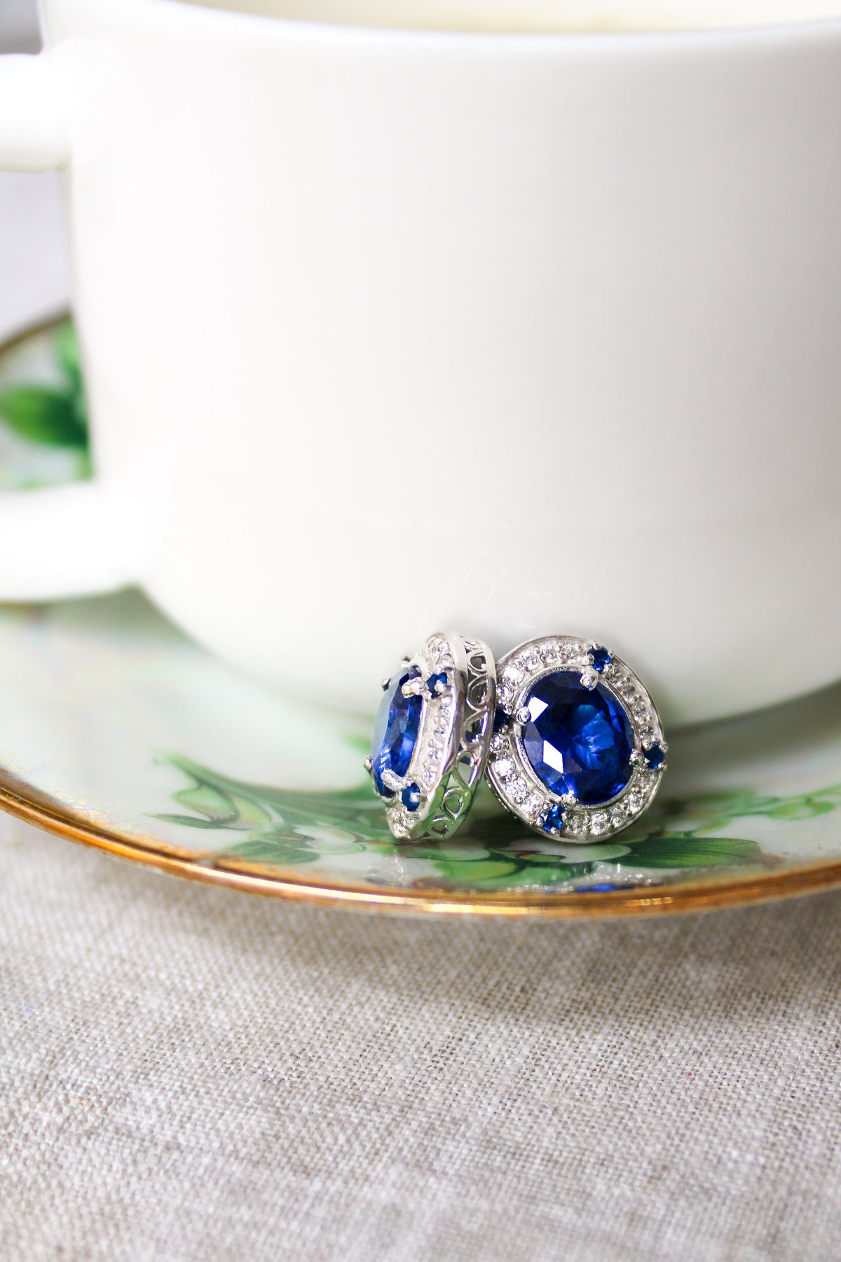 Detailed macro of silver Sovereign Stud Earrings showing radiant sapphire gemstone and luminous accents, Ether Jewelry