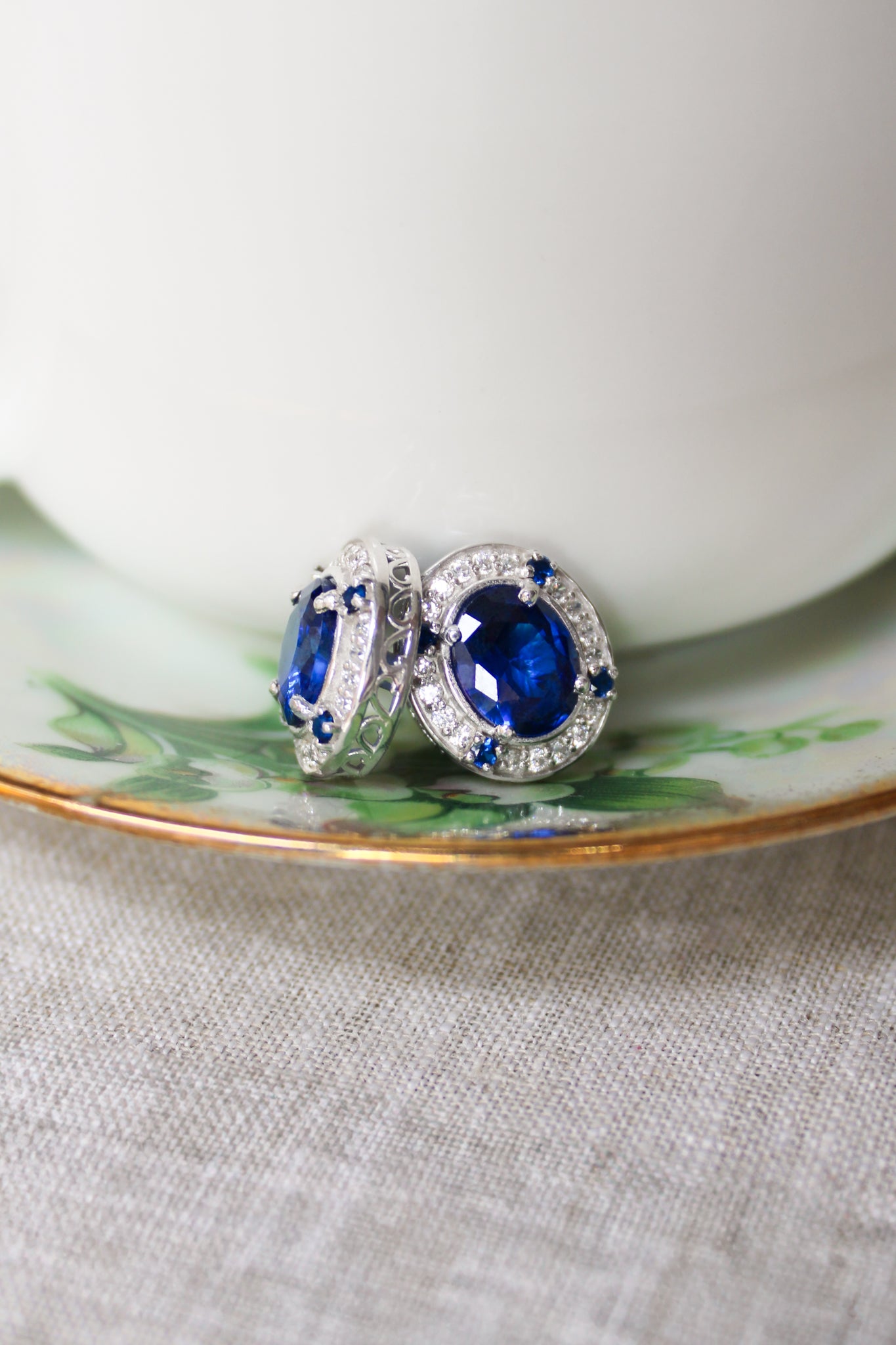 Detailed macro of silver Sovereign Stud Earrings showing radiant sapphire gemstone and luminous accents.