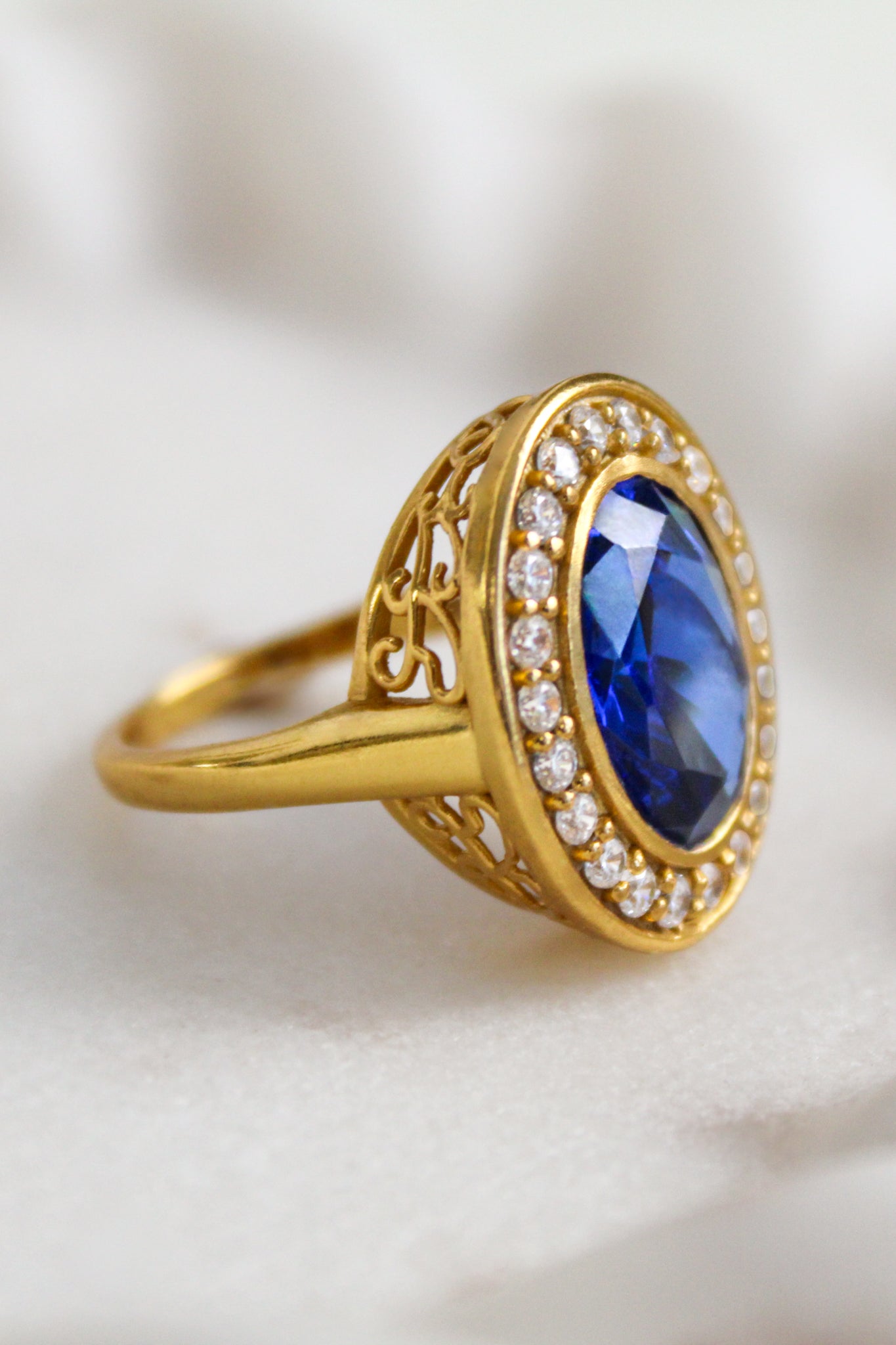 Marco shot of Gold ring with a blue gemstone and diamond accents on a white background