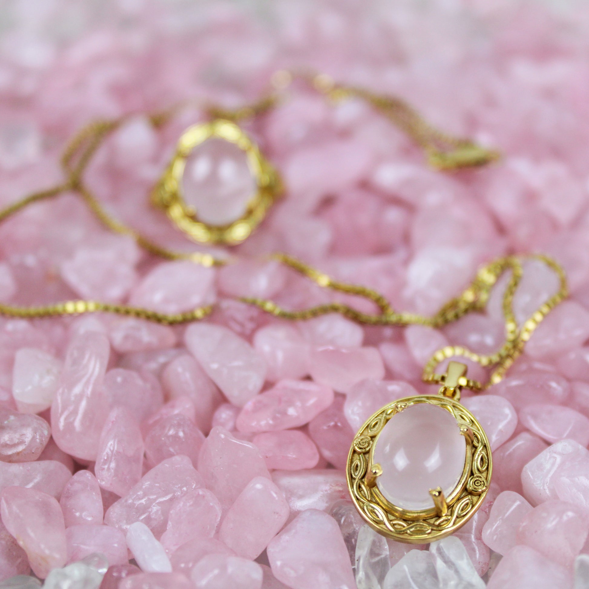Gold Romantic Heir necklace with a pink quartz pendant on a bed of pink stones