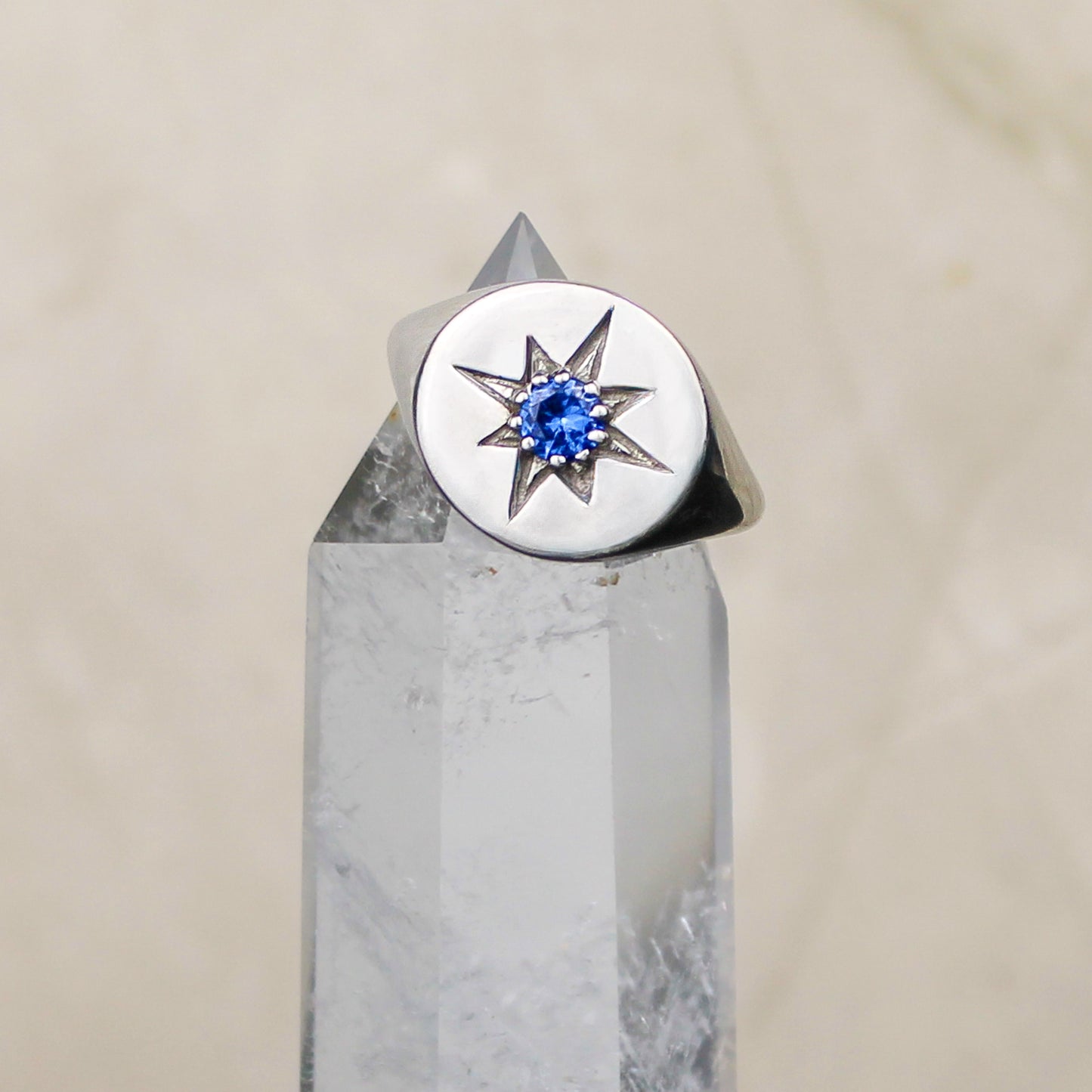 Sterling Silver star-shaped signet ring with a blue gemstone on a crystal base