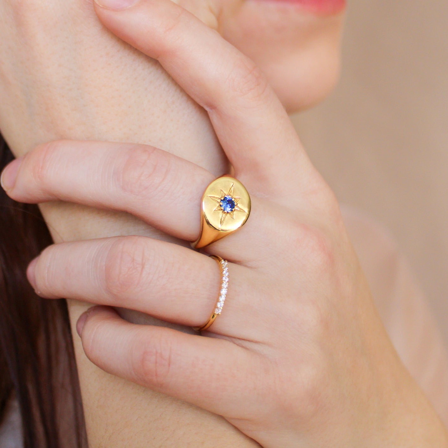 Wayfinder Ring in 18k gold vermeil on model holding hands close to face, engraved north star signet ring with blue CZ, Ether Jewelry