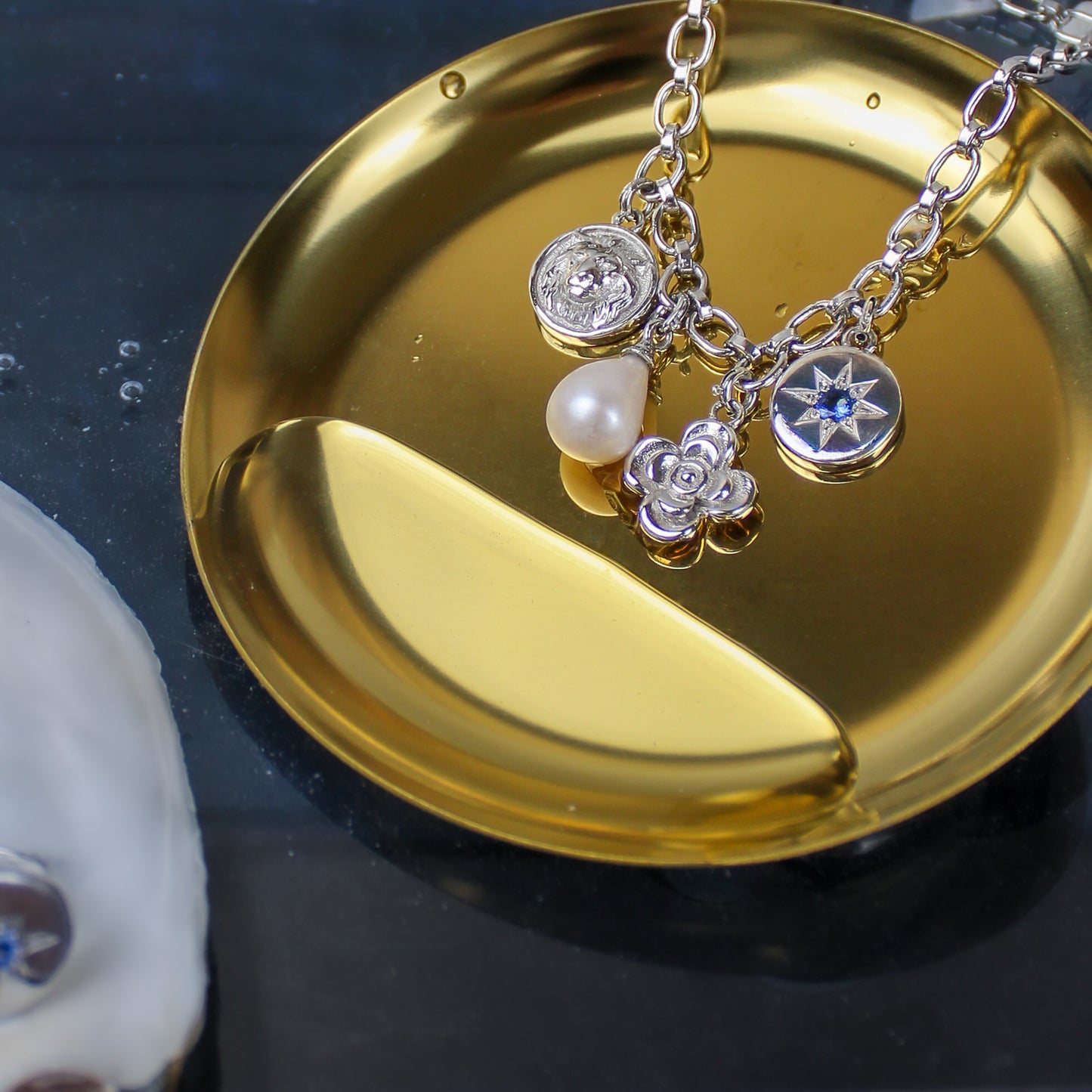 the achivist bracelet sterling Silver with charms on a gold dish