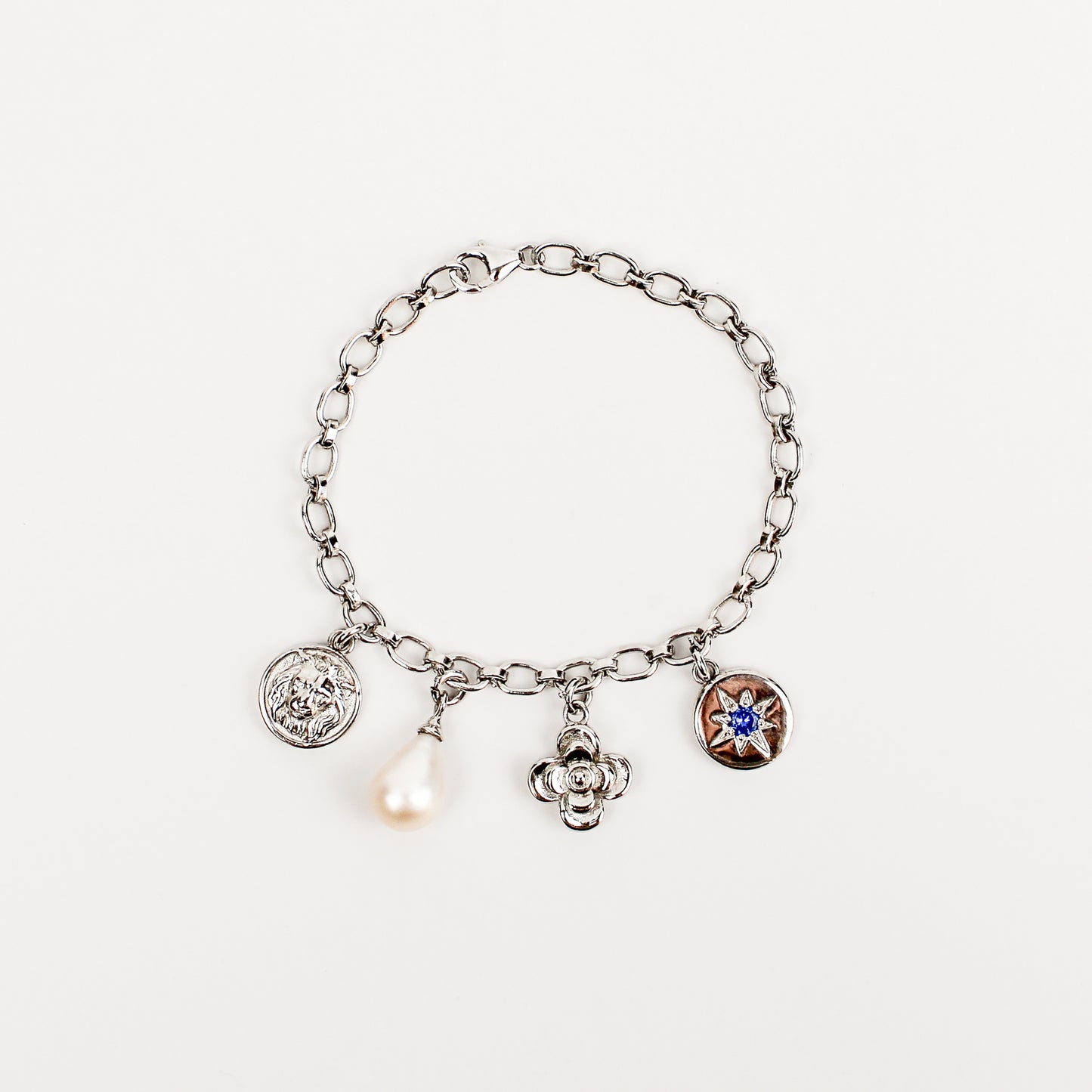 Archivist Bracelet in sterling silver, charm bracelet with lion coin, freshwater cultured pearl teardrop, flower and north star blue CZ coin charms on oval link chain, Ether Jewelry