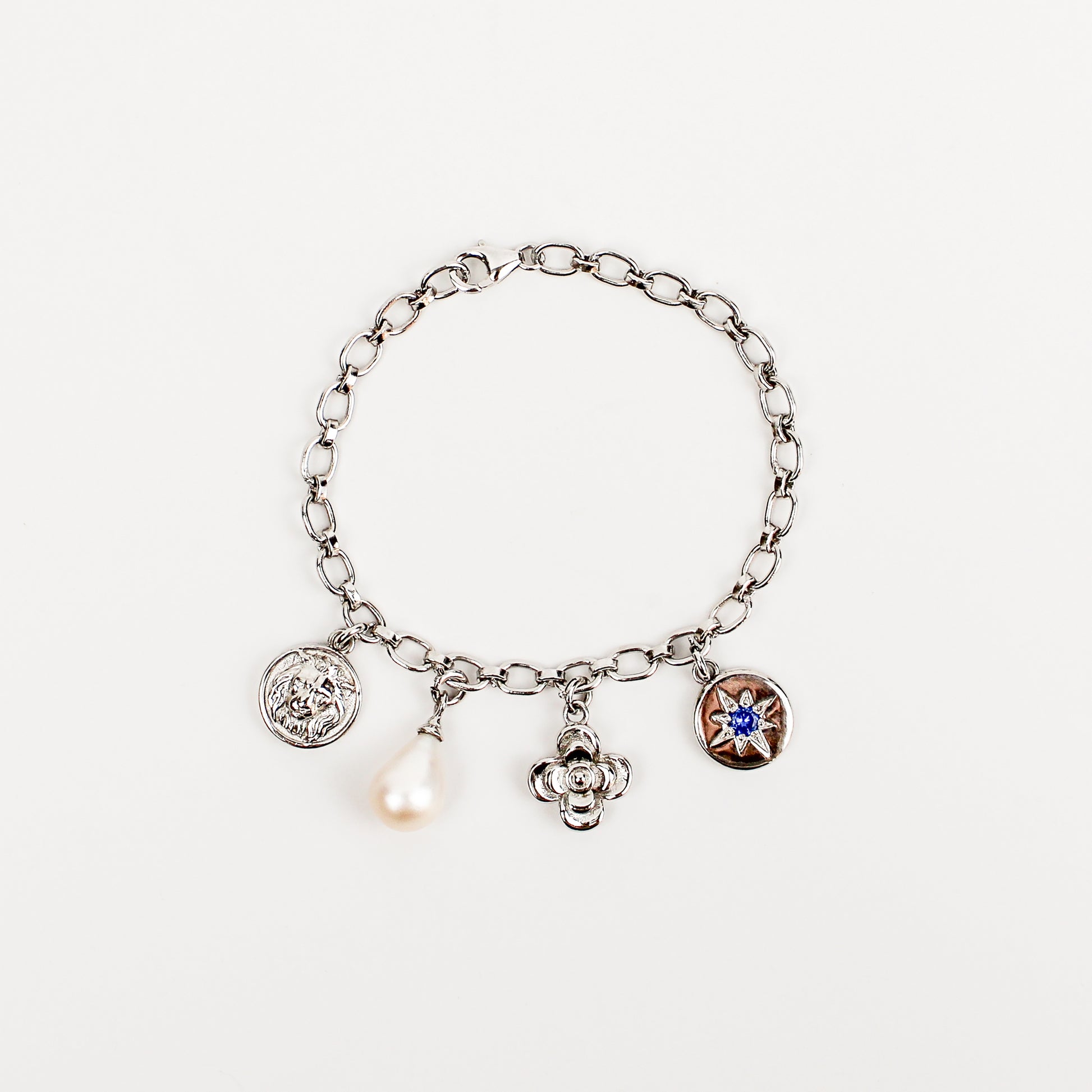 Archivist Bracelet in sterling silver, charm bracelet with lion coin, freshwater cultured pearl teardrop, flower and north star blue CZ coin charms on oval link chain, Ether Jewelry