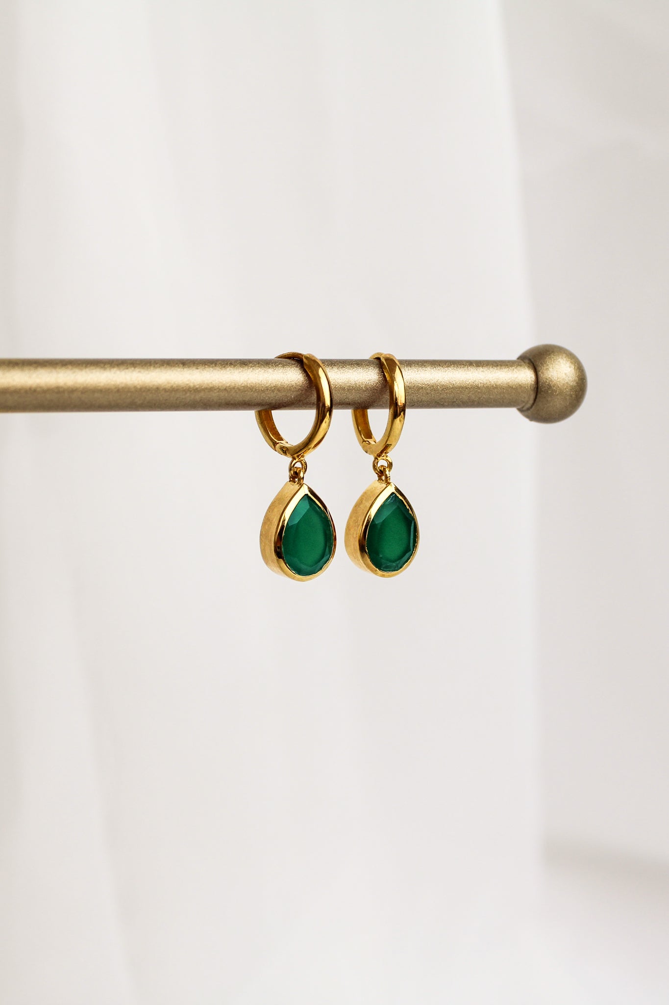 Devoted 18k gold vermeil earrings staged on brass jewelry bar display, green onyx teardrop huggie hoop earrings, Ether Jewelry