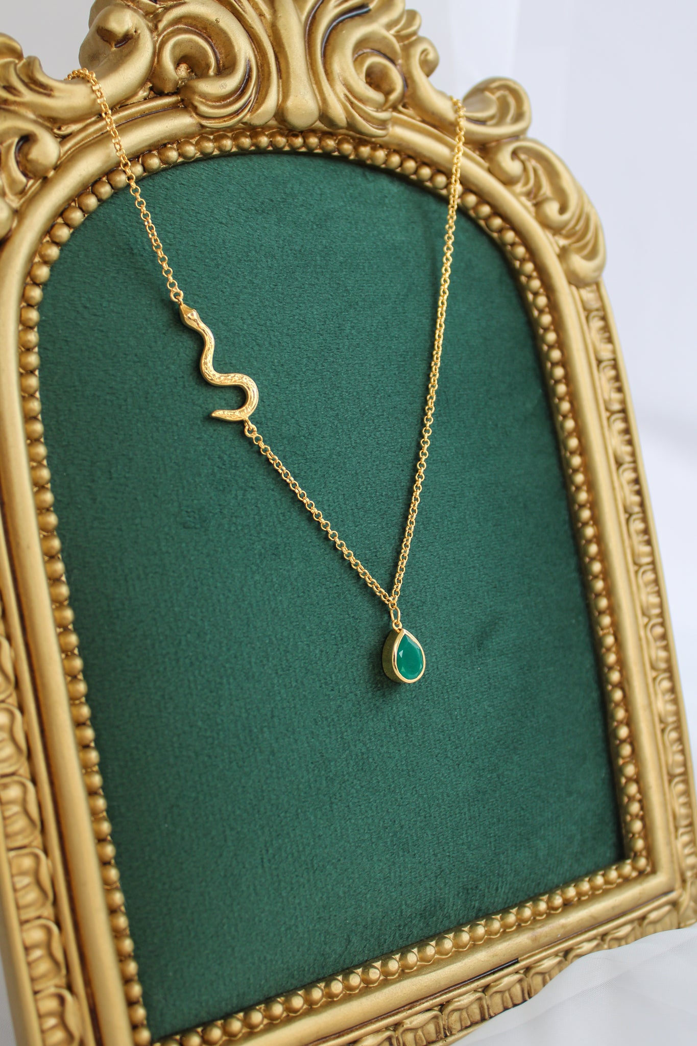 Devoted 18k gold vermeil necklace staged on vintage green fabric display, serpent chain with green onyx teardrop pendant, Ether Jewelry