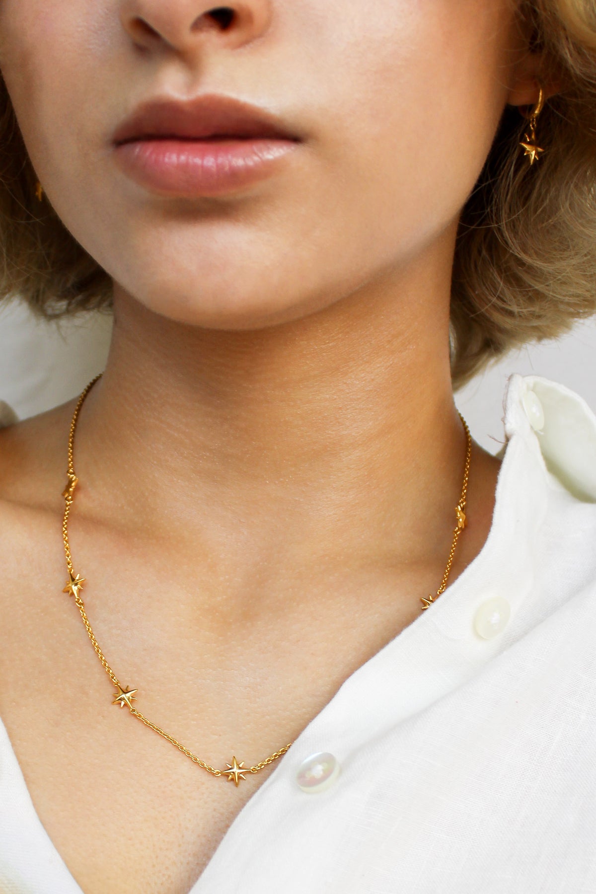 18k gold vermeil Juno Necklace on model front view, delicate cable chain with scattered solid north star charms, Ether Jewelry