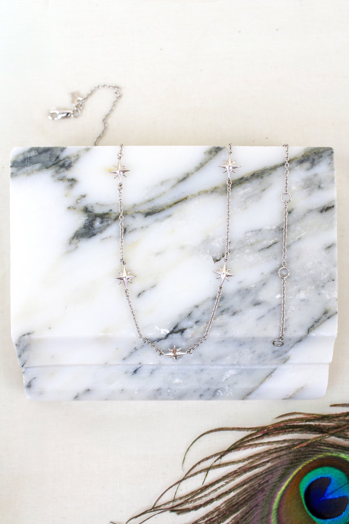 Juno Necklace sterling silver product photo, multi star charm station necklace, on marble with peacock feather, goddess juno, Ether Jewelry