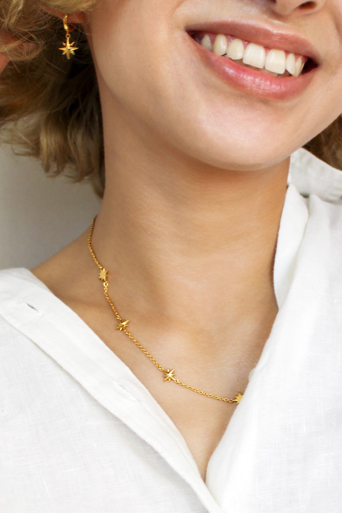 18k gold vermeil Juno Necklace on model smiling, front view, delicate cable chain with scattered solid north star charms, Ether Jewelry