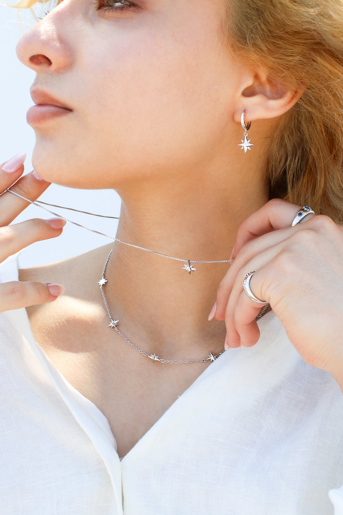 Juno Necklace in sterling silver on model styled with matching jewelry, multi north star charm station necklace, Ether Jewelry
