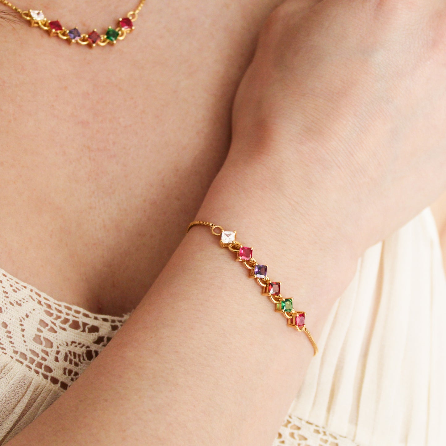 18k gold vermeil Linked Love Bracelet on model wrist against chest, square-cut REGARD acrostic CZ bracelet, Ether Jewelry